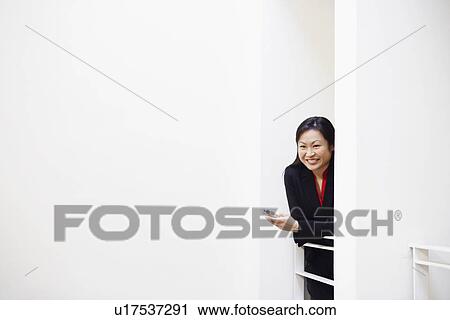 Businesswoman holding a mobile phone and smiling View Large Photo Image Stock Image - Businesswoman holding a mobile phone and smiling. Fotosearch