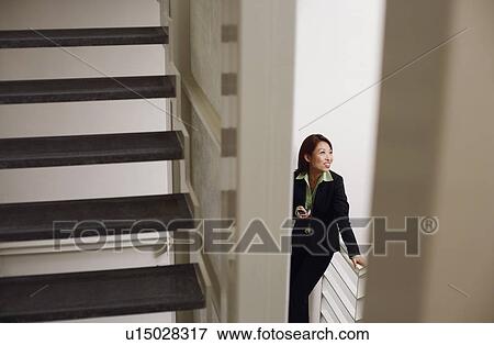 Stock Photo - High angle view of a businesswoman holding a mobile phone and smiling. Fotosearch