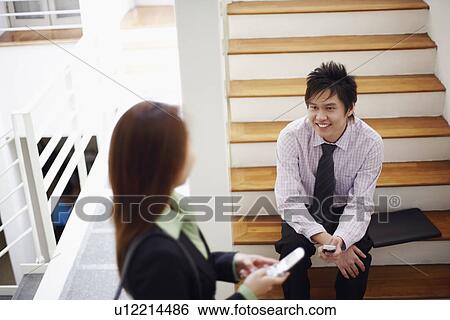 Stock Photograph - High angle view of a businesswoman talking to a businessman and smiling. Fotosearch