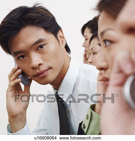 Portrait of a businessman talking on a mobile phone with his colleagues View Large Photo Image Picture - Portrait of a businessman talking on a mobile phone with his colleagues. Fotosearch