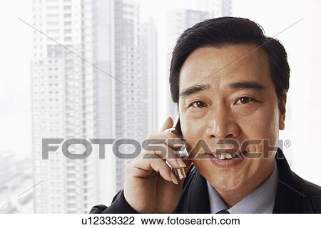 Stock Image - Portrait of a businessman talking on a mobile phone smiling. Fotosearch