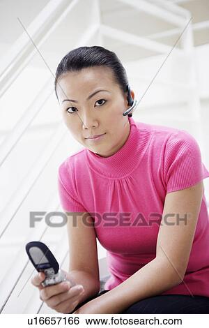Portrait of a businesswoman sitting on a staircase and holding a mobile phone View Large Photo Image Stock Photograph - Portrait of a businesswoman sitting on a staircase and holding a mobile phone. Fotosearch