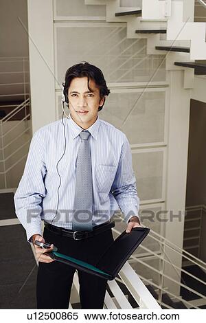 Portrait of a male customer service representative holding a file and a mobile phone View Large Photo Image Stock Photography - Portrait of a male customer service representative holding a file and a mobile phone. Fotosearch
