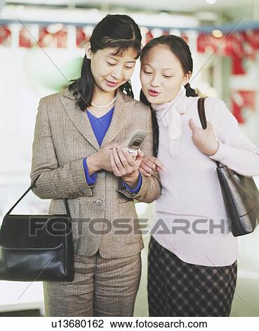 Stock Image - Two young women looking at a mobile phone. Fotosearch