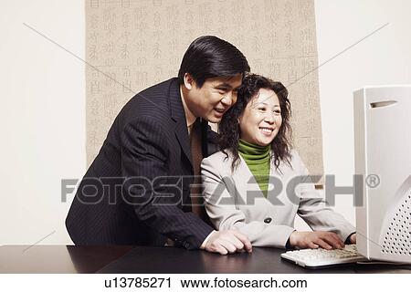 Businessman and a businesswoman using a computer View Large Photo Image Stock Image - Businessman and a businesswoman using a computer. Fotosearch