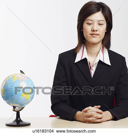 Picture - Businesswoman sitting with a globe in front of her. Fotosearch
