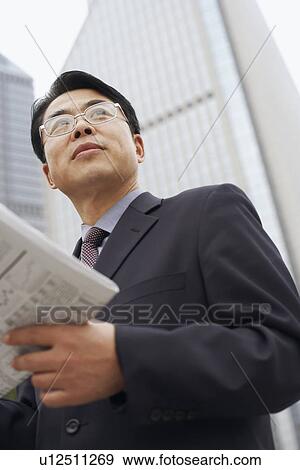 Stock Photo - Close-up of a businessman holding a newspaper. Fotosearch