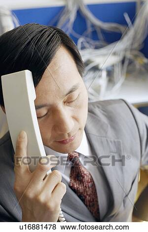 Stock Photo - Close-up of a businessman holding a telephone receiver in a server room. Fotosearch
