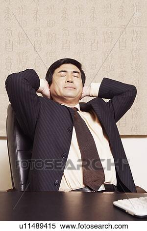 Close-up of a businessman sitting in an office with his hands behind his head View Large Photo Image Stock Photography - Close-up of a businessman sitting in an office with his hands behind his head. Fotosearch
