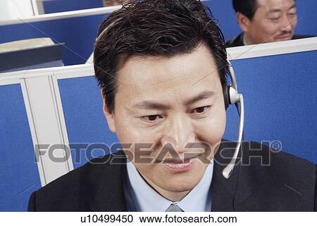 Stock Image - Close-up of a businessman wearing headsets. Fotosearch