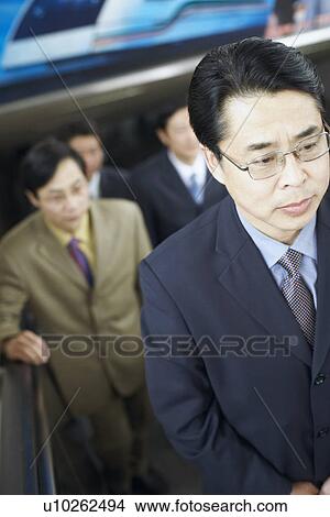 Picture - High angle view of a businessman standing on an escalator. Fotosearch
