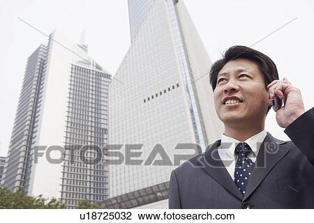Low angle view of a businessman talking on a mobile phone View Large Photo Image Stock Image - Low angle view of a businessman talking on a mobile phone. Fotosearch