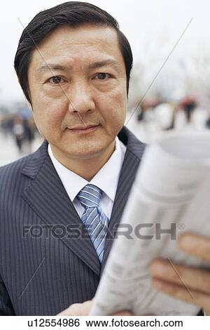 Portrait of a businessman holding a newspaper View Large Photo Image Stock Photograph - Portrait of a businessman holding a newspaper. Fotosearch