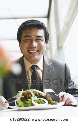 Stock Image - Portrait of a businessman seated at the table in a restaurant smiling. Fotosearch