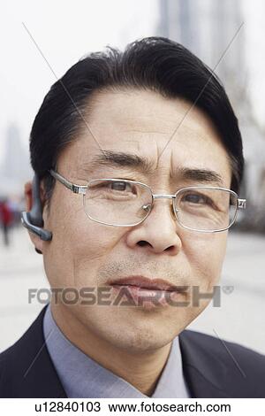 Stock Image - Portrait of a businessman wearing a hands free device. Fotosearch