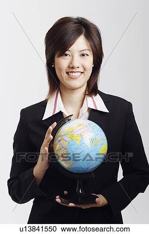 Stock Image - Portrait of a businesswoman holding a globe and smiling. Fotosearch