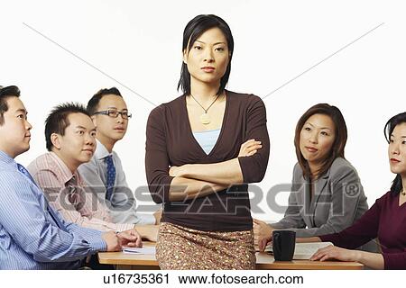 Portrait of a businesswoman leaning against a table with business executives sitting behind her View Large Photo Image Stock Image - Portrait of a businesswoman leaning against a table with business executives sitting behind her. Fotosearch