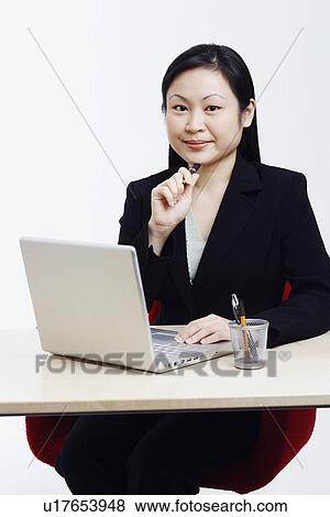 Stock Photo - Portrait of a businesswoman sitting in front of a laptop. Fotosearch