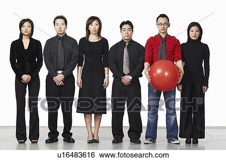 Stock Photograph - Portrait of a young man standing holding a ball with a group of business executives. Fotosearch