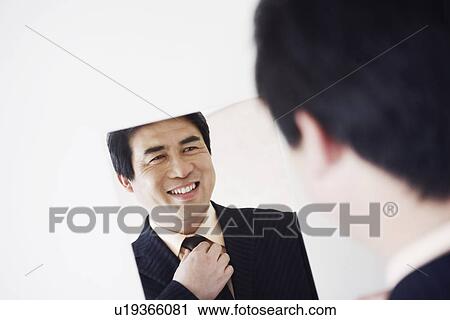 Rear view of a businessman looking into a mirror adjusting his tie View Large Photo Image Stock Image - Rear view of a businessman looking into a mirror adjusting his tie. Fotosearch