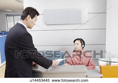 Side profile of a businessman standing in an office talking to the receptionist View Large Photo Image Stock Photography - Side profile of a businessman standing in an office talking to the receptionist. Fotosearch