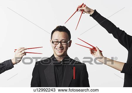 Three people holding chopsticks around a businessman View Large Photo Image Stock Image - Three people holding chopsticks around a businessman. Fotosearch