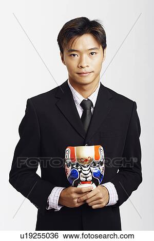 Stock Photograph - Portrait of a businessman holding a mask. Fotosearch