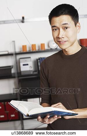 Stock Photo - Portrait of a businessman holding a book smiling. Fotosearch