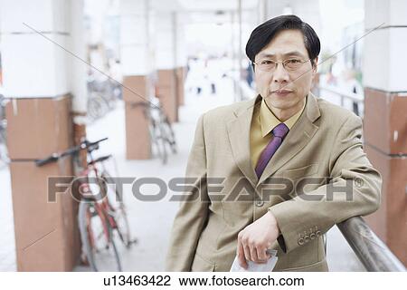 Stock Image - Portrait of a businessman leaning against a railing. Fotosearch