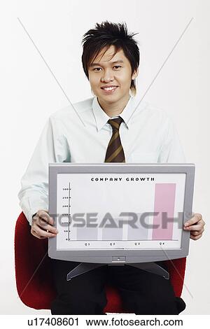 Stock Image - Portrait of a businessman sitting on a chair and holding a progress report. Fotosearch