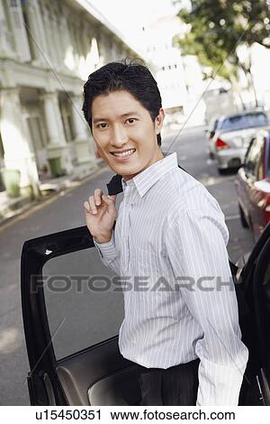 Portrait of a businessman standing near a car and smiling View Large Photo Image Stock Image - Portrait of a businessman standing near a car and smiling. Fotosearch