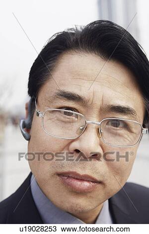 Stock Image - Portrait of a businessman wearing a hands free device. Fotosearch