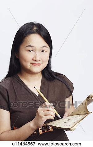 Portrait of a mid adult woman holding a book with a pencil and smiling View Large Photo Image Stock Photo - Portrait of a mid adult woman holding a book with a pencil and smiling. Fotosearch
