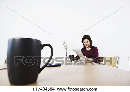 Picture - Businesswoman reading a newspaper. Fotosearch