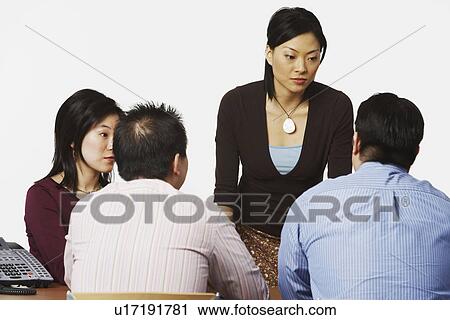 Stock Image - Businesswoman talking to her colleagues in a conference room. Fotosearch