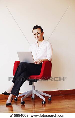 Stock Photo - Businesswoman using a laptop and smiling. Fotosearch