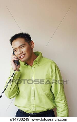 Stock Photo - Close-up of a businessman talking on the telephone and smiling. Fotosearch