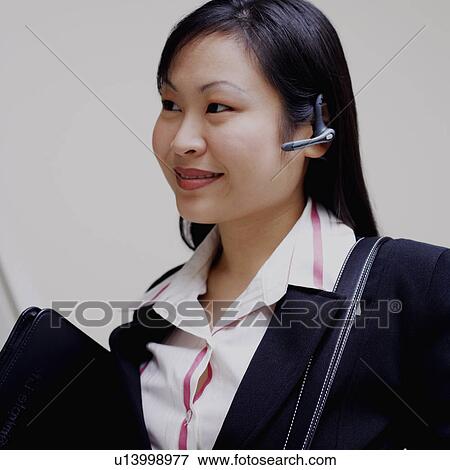 Stock Photo - Close-up of a businesswoman holding a handbag and smiling. Fotosearch