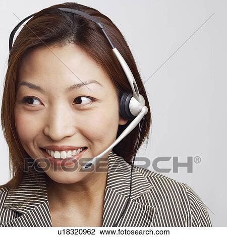 Stock Image - Close-up of a businesswoman wearing a headset and smiling. Fotosearch