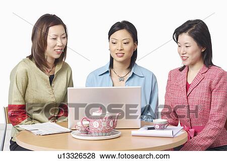 Stock Photo - Close-up of three businesswomen in front of a laptop. Fotosearch