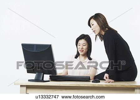 Close-up of two businesswomen looking at a computer View Large Photo Image Stock Photo - Close-up of two businesswomen looking at a computer. Fotosearch