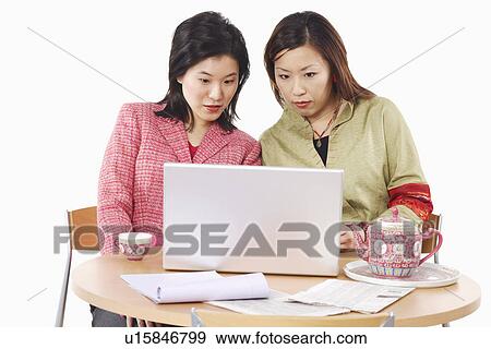 Close-up of two businesswomen using a laptop View Large Photo Image Stock Photo - Close-up of two businesswomen using a laptop. Fotosearch