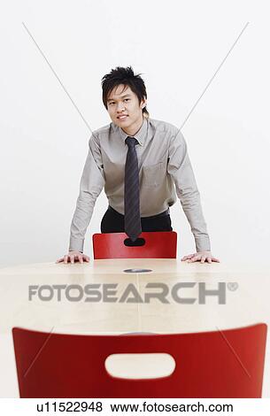 Stock Photo - Portrait of a businessman bending forward over a conference table and smiling. Fotosearch