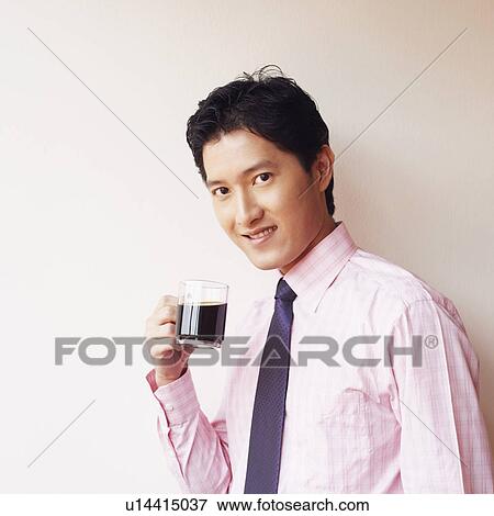 Stock Photo - Portrait of a businessman holding a cup of black tea and smiling. Fotosearch