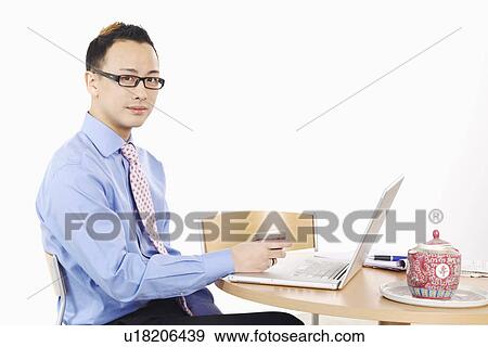Stock Photo - Portrait of a businessman holding a cup in front of a laptop. Fotosearch