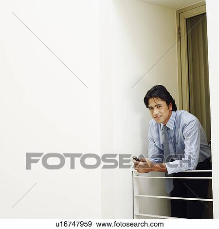 Portrait of a businessman holding a mobile phone and smiling View Large Photo Image Stock Photo - Portrait of a businessman holding a mobile phone and smiling. Fotosearch