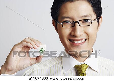 Stock Photograph - Portrait of a businessman holding a marble cube and smiling. Fotosearch