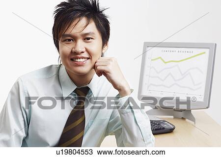 Stock Image - Portrait of a businessman smiling with a progress report in the background. Fotosearch