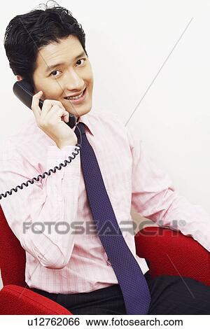 Stock Photograph - Portrait of a businessman talking on the telephone and smiling. Fotosearch