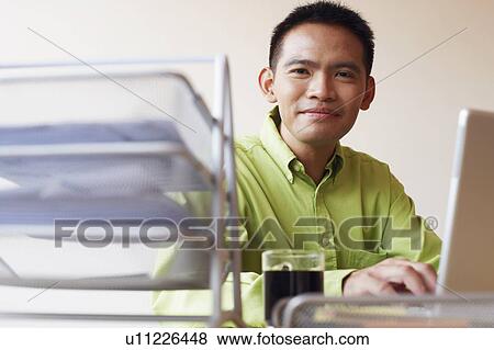 Stock Photo - Portrait of a businessman using a laptop and smiling. Fotosearch